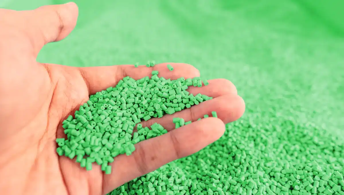 Hand holding green polymer pellets